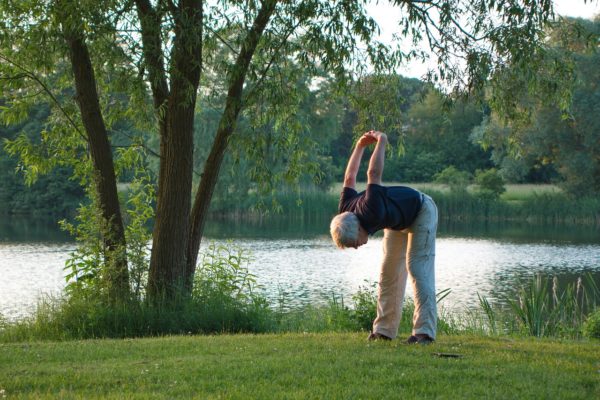 man in yoga pose outdoors by lake